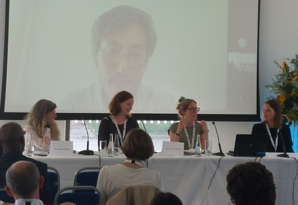 Photo of the Mid-term Academic Conference picturing Prof. Sarah Whatley, Prof. Aoife McGrath, Dr. Victoria Durrer and Prof. Delia Ferri with Sho Shibata on the screen behind.