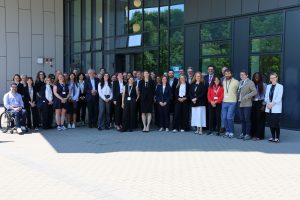 A group photo of all the conference attendees standing outside in the sun at Maynooth University