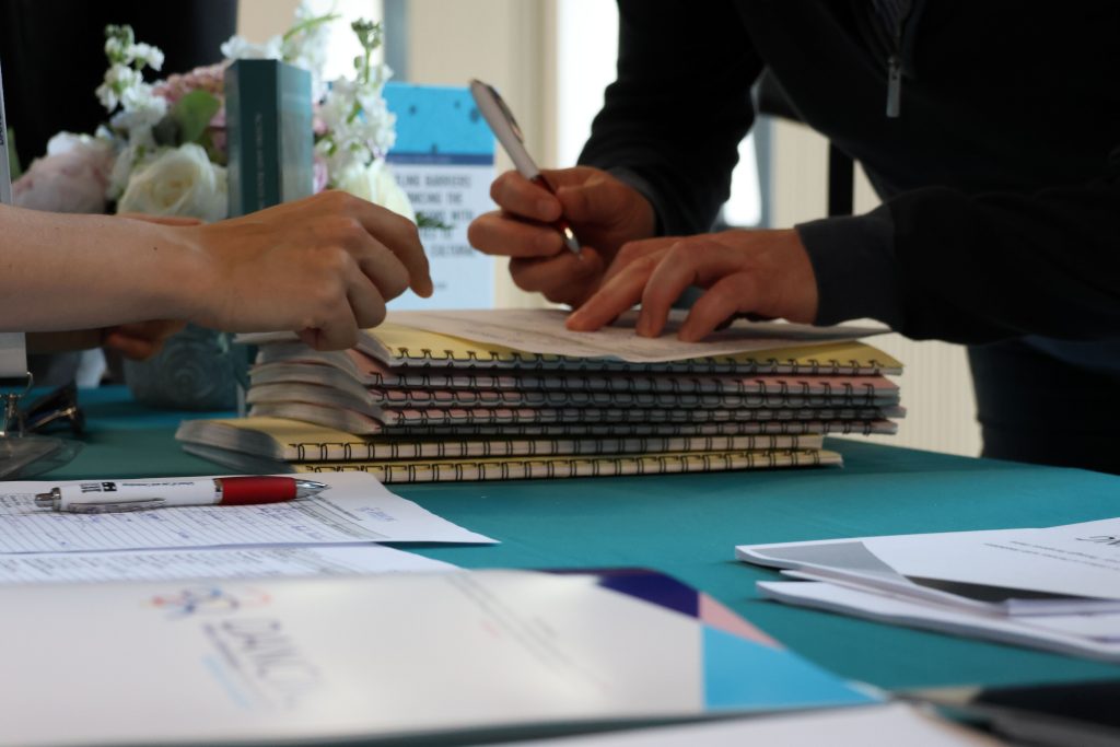 Registration desk with participant signing the attendance sheet.